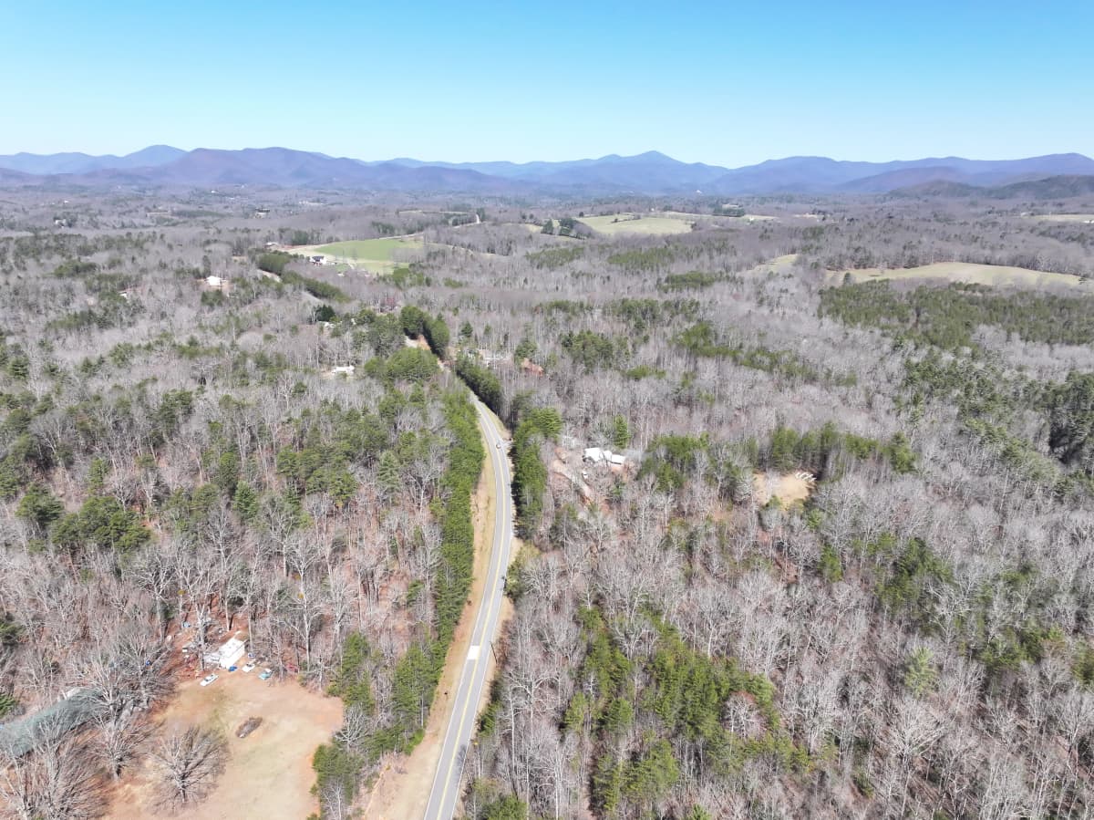 Aerial drone view of the wooded property and road with the Blue Ridge foothills beyond